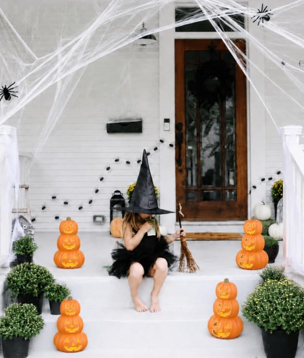 A stacked jack-o'-lantern glowing on an autumn porch